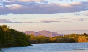 Mountains at sunset with a lake in the foreground.